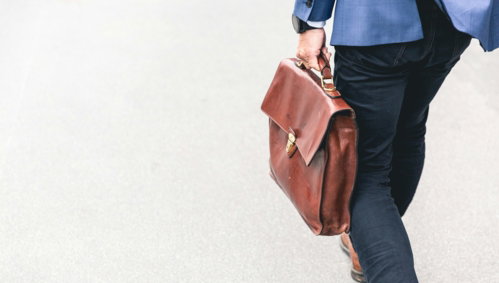 person walking holding brown leather bag